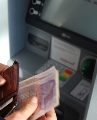 Em imagem ilustrativa, pessoa saca dinheiro em banco.