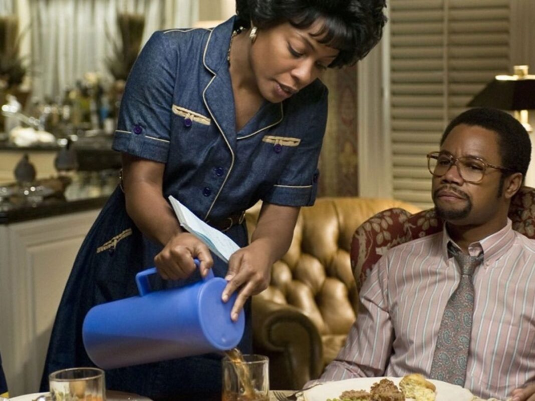 Uma mulher está de pé servindo café ao homem que está sentado na mesa.