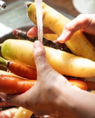 Em imagem ilustrativa, pessoa lava alimentos em água em abundância