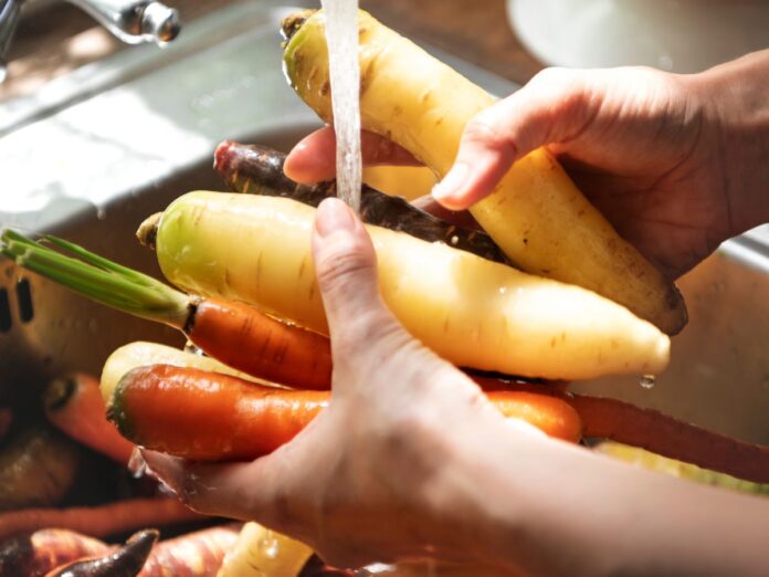 Em imagem ilustrativa, pessoa lava alimentos em água em abundância
