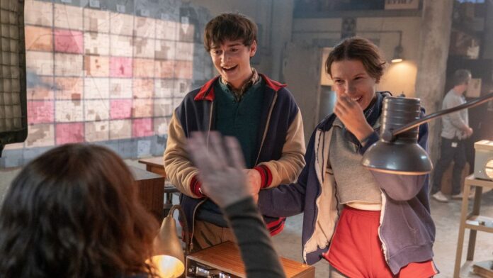 Esta é uma imagem colorida, em ambiente interno, que captura um momento de aparente alegria e intensa atividade de investigação, tipicamente associado à série Stranger Things.