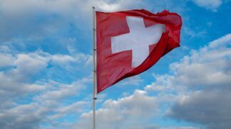 Imagem ilustrativa da bandeira da Suíça a céu aberto.