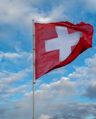 Imagem ilustrativa da bandeira da Suíça a céu aberto.