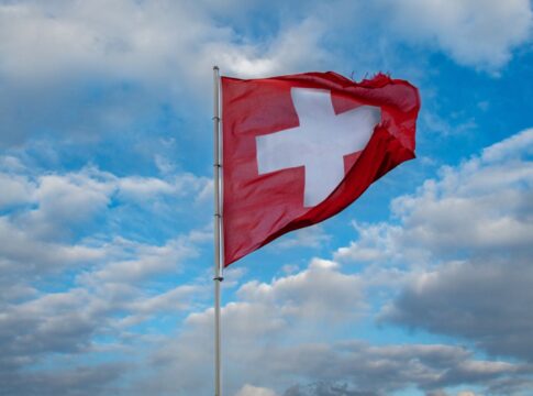 Imagem ilustrativa da bandeira da Suíça a céu aberto.