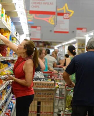mulher pega produto em prateleira de supermercado