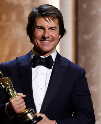 Ator Tom Cruise veste smoking e sorri com um Oscar honorário nas mãos, em evento especial da Academia
