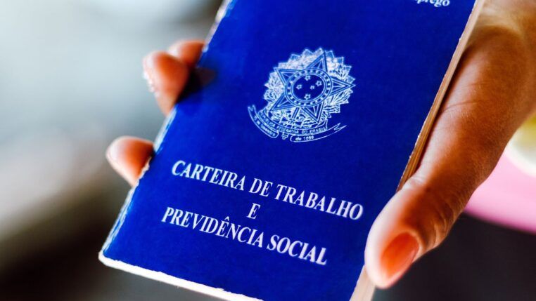 Em imagem ilustrativa, pessoa segura em suas mãos, uma carteira de trabalho brasileira.