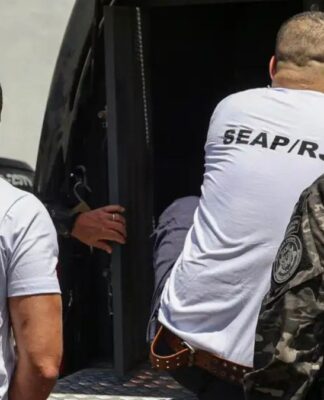 homens entrando em veículo policial para serem transferidos