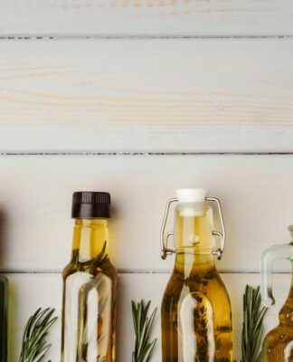 Quatro frascos de vidro com azeite e vinagre dentro.