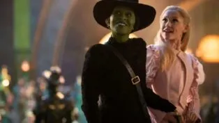 As personagens Elphaba e Glinda olham juntos de mãos dadas para algo que deixa eles felizes