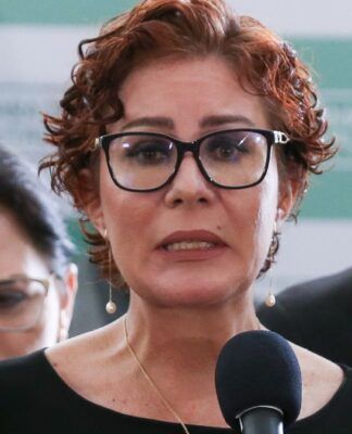 Esta é uma foto em close-up, tirada em um evento em ambiente interno, que foca na deputada federal Carla Zambelli enquanto ela discursa.
