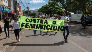 mulheres segurando faixa escrito "contra o feminicídio"