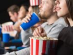 Em imagem ilustrativa, pessoas assistem ao cinema com pipoca