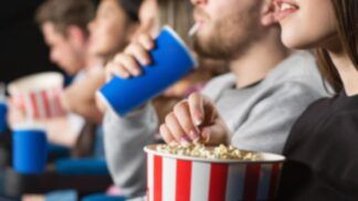 Em imagem ilustrativa, pessoas assistem ao cinema com pipoca