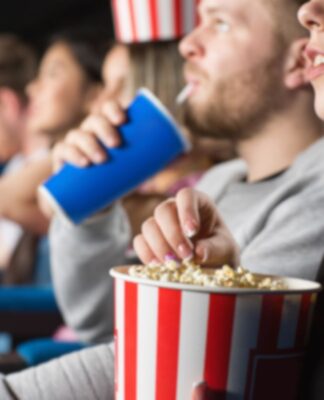 Em imagem ilustrativa, pessoas assistem ao cinema com pipoca