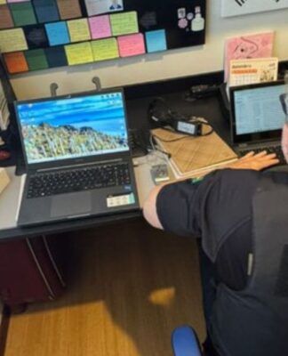 Policial acessa notebook numa escrivaninha na casa de um dos suspeitos