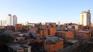 Imagem de favela no primeiro plano, com prédios de classe média ao fundo