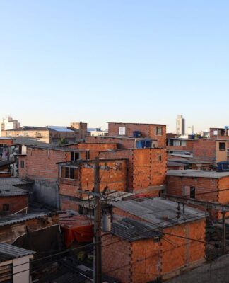 Imagem de favela no primeiro plano, com prédios de classe média ao fundo