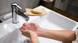 Duas mãos recebem água de uma torneira