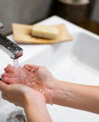Duas mãos recebem água de uma torneira