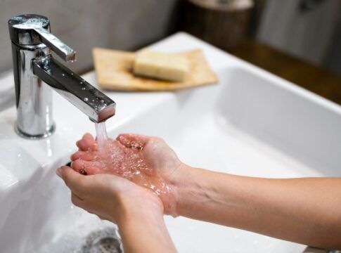Duas mãos recebem água de uma torneira