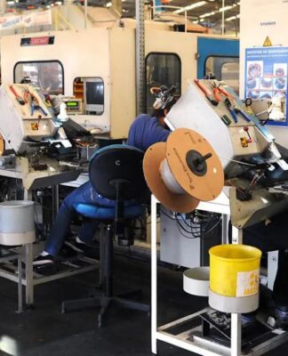 Homens operam máquinas em fábrica