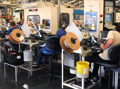 Homens operam máquinas em fábrica