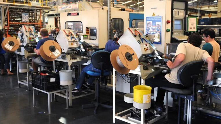 Homens operam máquinas em fábrica