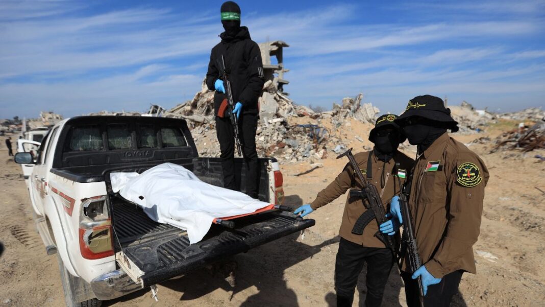 Militantes do Hamas e da Jihad Islâmica mostram corpo encoberto por lona branca sobre uma picape.