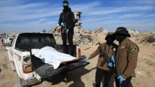 Militantes do Hamas e da Jihad Islâmica mostram corpo encoberto por lona branca sobre uma picape.