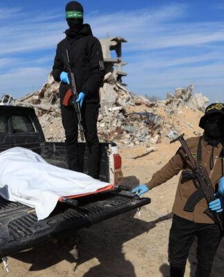 Militantes do Hamas e da Jihad Islâmica mostram corpo encoberto por lona branca sobre uma picape.