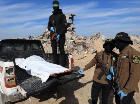 Militantes do Hamas e da Jihad Islâmica mostram corpo encoberto por lona branca sobre uma picape.