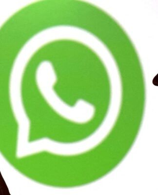 Pessoa olha para seu celular enquanto aparece o logo do Whatsapp ao fundo