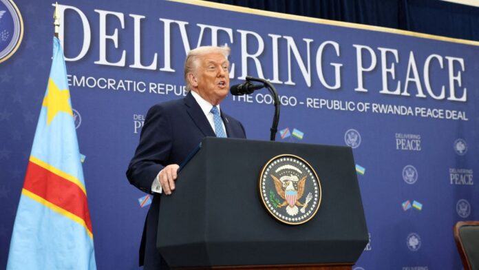 Donald Trump fala ao microfone à frente de painel onde está escrita a mensagem 