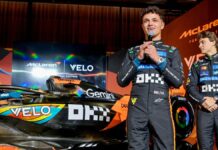Lando Norris fala ao microfone ao lado da sua McLaren e do companheiro Oscar Piastri em evento pré-GP