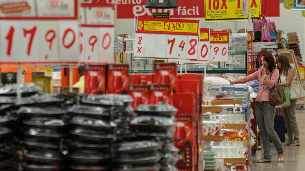 Imagem dentro de um mercado, mostrando várias placas de preços e alimentos nas prateleiras