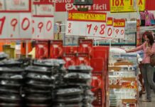 Imagem dentro de um mercado, mostrando várias placas de preços e alimentos nas prateleiras