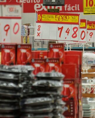 Imagem dentro de um mercado, mostrando várias placas de preços e alimentos nas prateleiras