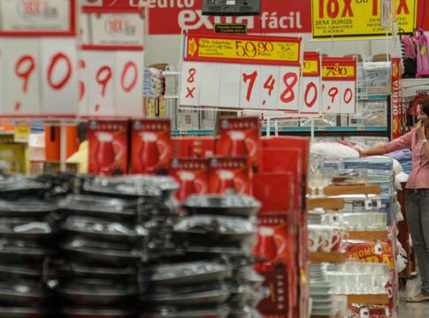 Imagem dentro de um mercado, mostrando várias placas de preços e alimentos nas prateleiras