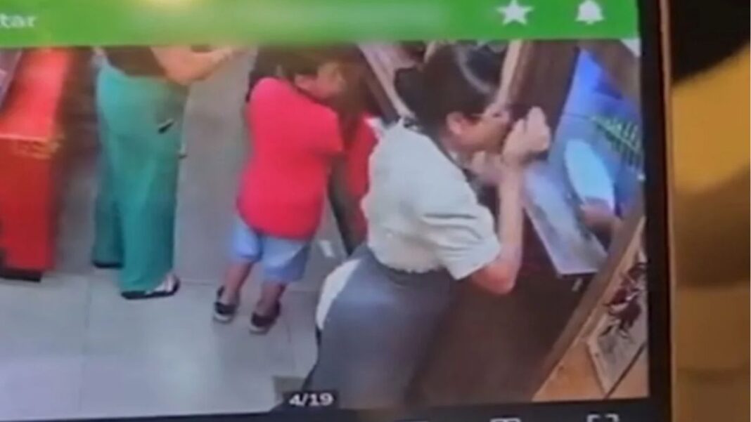 Foto da tela de um celular mostrando o instante em que a funcionária é golpeada no rosto