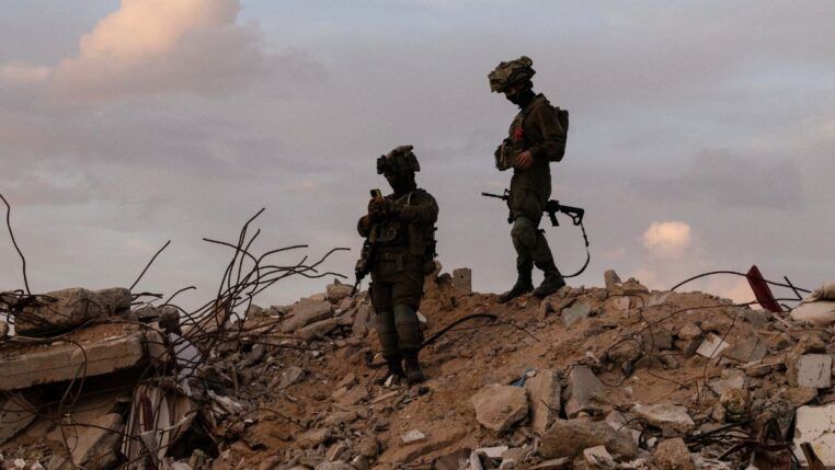Dois soldados israelenses em cima de escombros na região de Gaza
