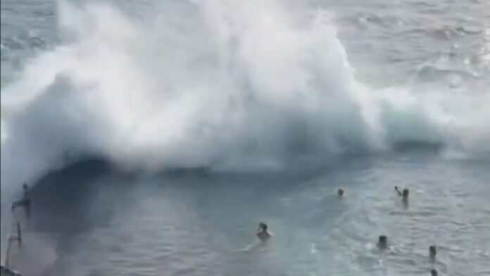 Momento em que uma onda gigante se choca contra a estrutura de uma piscina natural