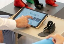 Close dos braços de dois funcionários de uma empresa, com um deles mexendo na tela de um tablet