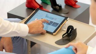 Close dos braços de dois funcionários de uma empresa, com um deles mexendo na tela de um tablet