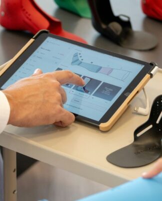 Close dos braços de dois funcionários de uma empresa, com um deles mexendo na tela de um tablet