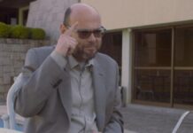 Foto de Marcelo (homem careca de terno), apontando para a cabeça durante entrevista