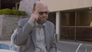 Foto de Marcelo (homem careca de terno), apontando para a cabeça durante entrevista