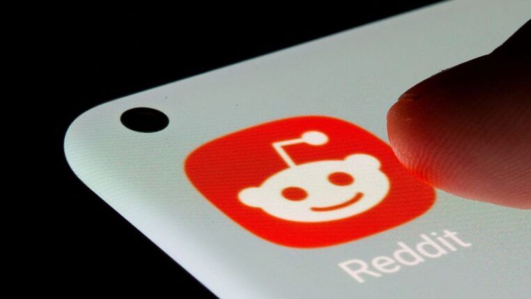 Dedo prestes a pressionar o ícone do aplicativo Reddit