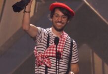 Homem vestido com roupas de mímico levantando troféu