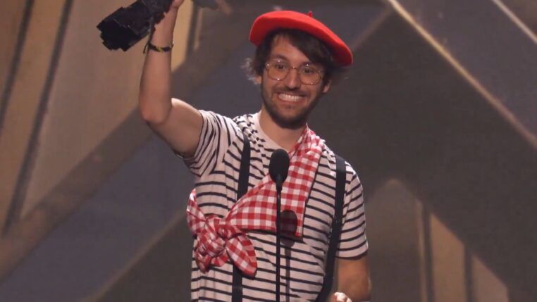 Homem vestido com roupas de mímico levantando troféu